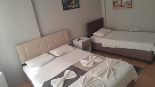 Cette petite chambre comprend 2 lits avec des draps blancs. dans l'établissement M.H.T, à Edirne