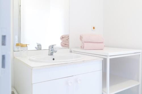 une salle de bain blanche avec un lavabo et un miroir dans l'établissement Bel appartement idéalement situé centre-ville Angers, à Angers