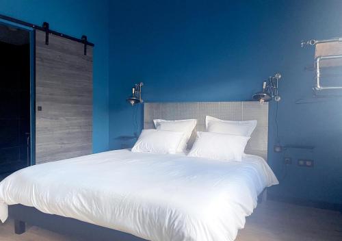 a blue bedroom with a white bed with white pillows at NUITS D'EXIL in Gérardmer