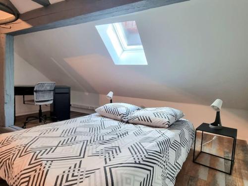 ein Schlafzimmer mit einem Bett und einem Dachfenster in der Unterkunft Duplex de l'Arbre de la Liberté in Guebwiller