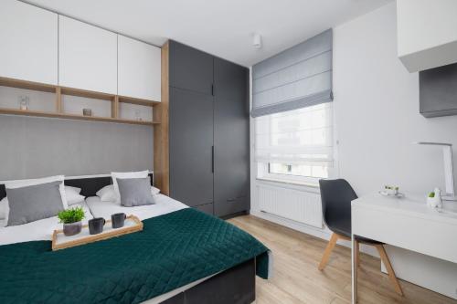um quarto com uma cama com um cobertor verde e uma secretária em Black and Grey Apartment in Cracow with Balcony, Parking and Desk by Renters em Cracóvia