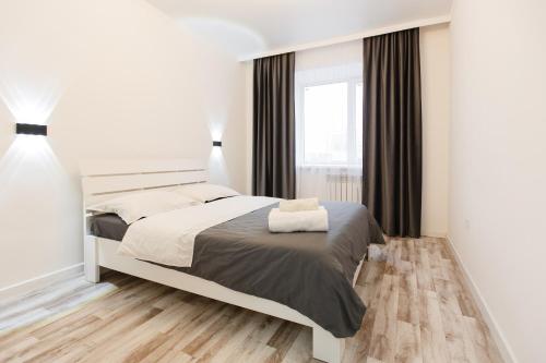biała sypialnia z łóżkiem i oknem w obiekcie Уютная двухкомнатная квартира w mieście Kokczetaw