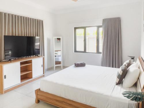a white bedroom with a large bed and a flat screen tv at Beachwalk Residence - Trou-aux-Biches in Trou aux Biches