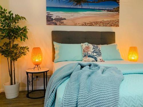 a bedroom with a bed with a blue blanket and two lamps at Paradise Island Resort & Gardens - Gold Coast Surfers Paradise in Gold Coast