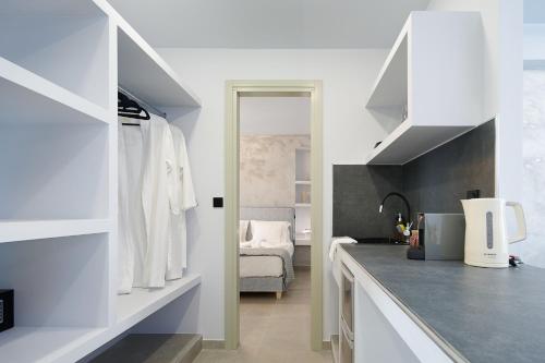 a kitchen with white cabinets and a room with a bed at Sapphire Kythnos Suites in Mérikhas