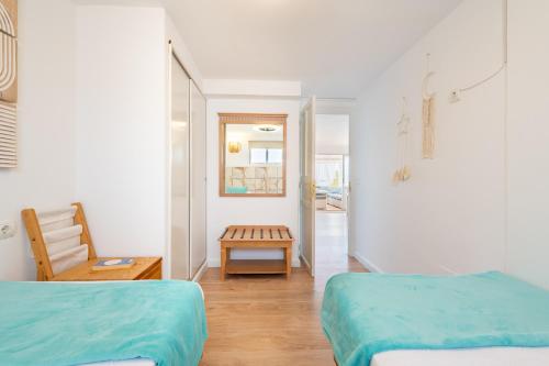 Habitación blanca con 2 camas y mesa en Beachfront Penthouse, en Colònia De Sant Jordi
