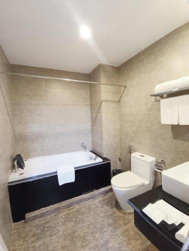 a bathroom with a tub and a toilet and a sink at Mường Thanh Grand Dien Bien Phu Hotel in Diện Biên Phủ