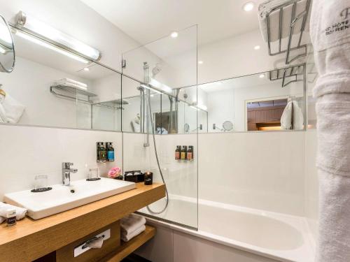 a white bathroom with a sink and a shower at Grand Hôtel Roi René Aix en Provence Centre - MGallery in Aix-en-Provence