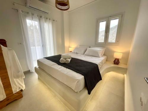 a white bedroom with a large bed with a black blanket at Seaclusion Santorini in Kamari