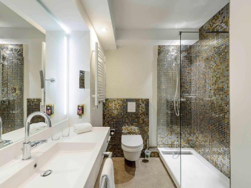 ein Bad mit einem Waschbecken, einem WC und einer Dusche in der Unterkunft Ibis Styles Regensburg in Regensburg
