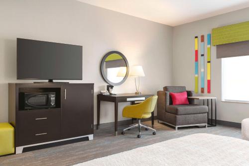 a hotel room with a tv and a chair and a desk at Hampton Inn & Suites York South in York