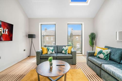 a living room with two couches and a table at Tottenham- Exquisite 4-Bed Retreat with Ping Pong and Pool - Sleeps 7, Free Parking, Contractors & Long Stays Welcome in London