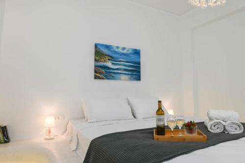 a white bedroom with a bed with a bottle of wine at Seaward in Kamari