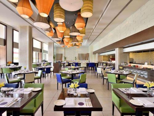 a dining room with tables and chairs and lights at Novotel Imagicaa Khopoli in Khopoli
