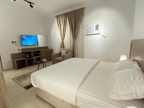 a bedroom with a white bed and a television at نايتس للوحدات المفروشة in Tabuk