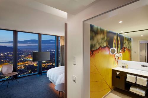 a hotel room with a bed and a bathroom with a view at HYPERION Hotel Basel in Basel