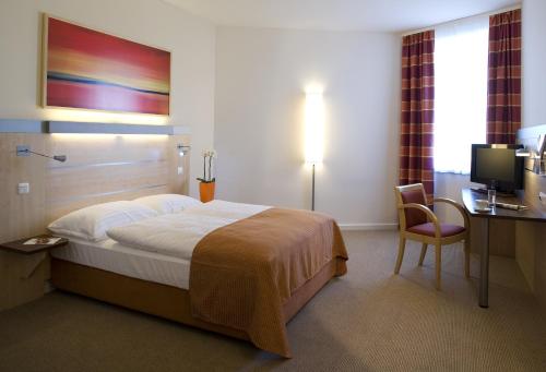 a hotel room with a bed and a desk and a television at Vienna House Easy by Wyndham Bratislava in Bratislava