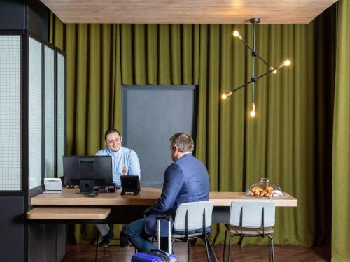 twee mannen aan een tafel voor een computer bij Aparthotel Adagio access Palaiseau Saclay in Palaiseau