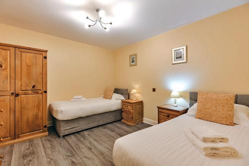 a bedroom with two beds and a wooden cabinet at Finest Retreats - Netley Hall - Mulberry in Dorrington