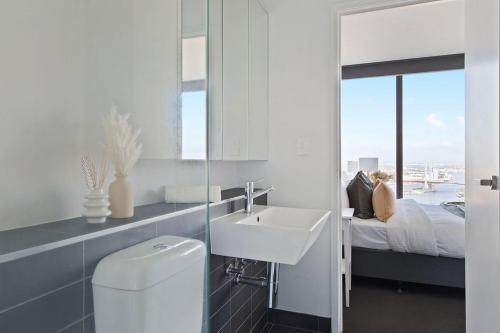 a white bathroom with a sink and a bed at A Modern 2BR Apt with Harbour Views FREE Parking in Melbourne