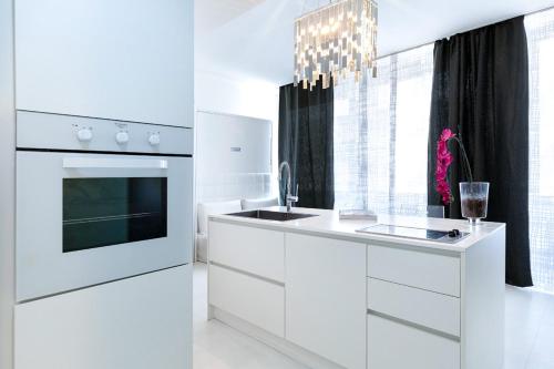 a kitchen with white cabinets and a sink and a chandelier at The Boutique Houses Milan - Galleria - With Private Parking in Milan