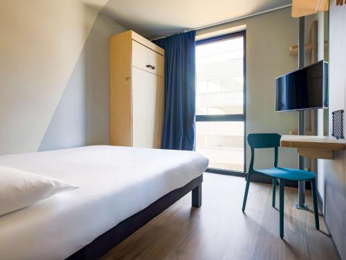 a bedroom with a bed and a chair and a window at ibis Budget La Rochelle Centre in La Rochelle