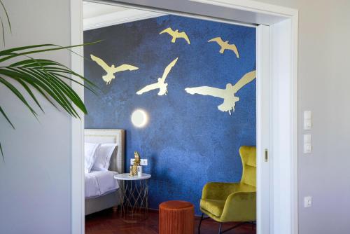 a bedroom with a blue wall with birds painted on it at Pafsilipon Suites in Ermoupoli