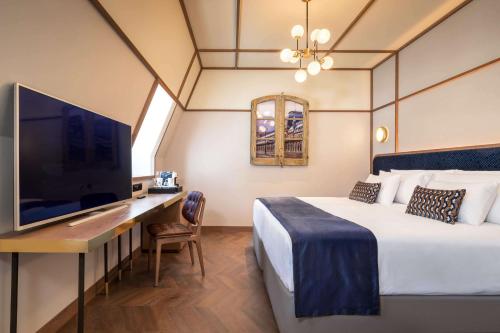 a hotel room with a bed and a desk with a tv at Canfranc Estación, a Royal Hideaway Hotel - Gran Lujo in Canfranc-Estación