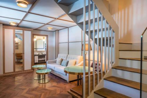a living room with a couch and a staircase at Canfranc Estación, a Royal Hideaway Hotel - Gran Lujo in Canfranc-Estación