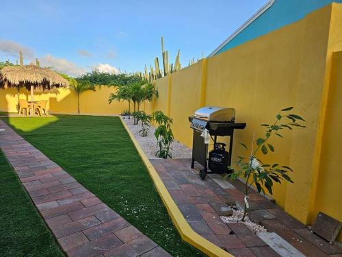 a grill next to a yellow wall with a yard at Yellow Cunucu-4 Bedrooms House in Paraguaná
