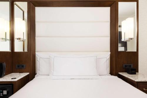 a bedroom with a white bed and two mirrors at Hilton Boston Park Plaza in Boston