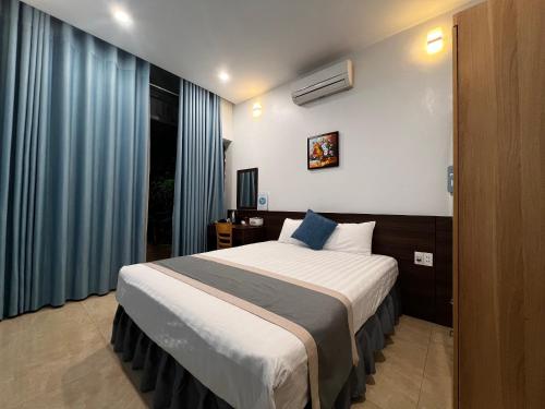 Schlafzimmer mit einem großen Bett und blauen Vorhängen in der Unterkunft Happy House Moc Chau in Mộc Châu