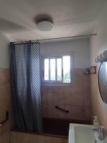 La salle de bains est pourvue d'un rideau de douche et d'une fenêtre. dans l'établissement Bel appartement 3 chambres 9 mn de la plage à pieds Juan les pins, à Antibes