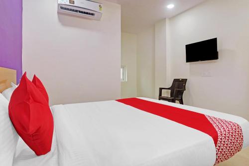1 dormitorio con 1 cama blanca con almohadas rojas y TV en Langar Houz Near Golconda Fort en Haidar Sāhibgūda
