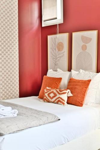 - une chambre avec des murs rouges et un lit avec des oreillers orange dans l'établissement Studio Cosy près de Montparnasse, à Paris