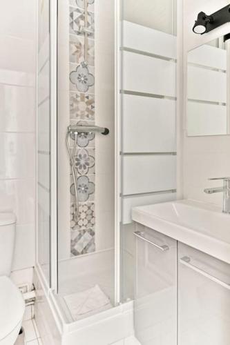une salle de bain blanche avec douche et toilettes dans l'établissement Studio Cosy près de Montparnasse, à Paris