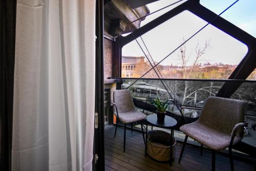 a balcony with two chairs and a table and a window at London Hotel Yerevan in Yerevan