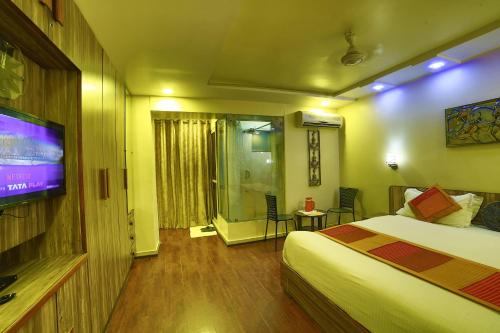 Una habitación de hotel con una cama y un televisor de pantalla plana. en Shaleen Elegance Homestay Nakki Lake 400 meters, en Mount Abu
