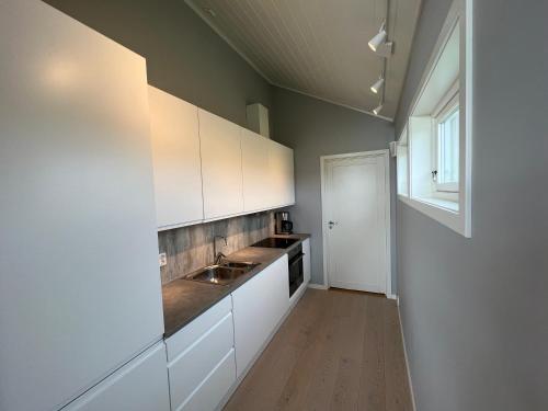 a kitchen with white cabinets and a sink and a window at Moderne feriehus i Bud in Bud