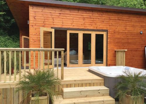 a house with a hot tub on a deck at Herons Lake Retreat in Caerwys