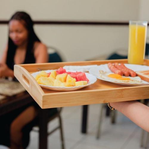 a tray of fruit on a table with a woman at MAYFAIR in Dar es Salaam