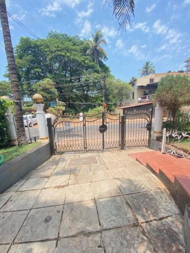 a black gate in a yard with trees and a building at Felix Homestay Enclave in Panaji