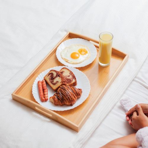 a tray with a breakfast of eggs and sausage and a glass of orange juice at MAYFAIR in Dar es Salaam