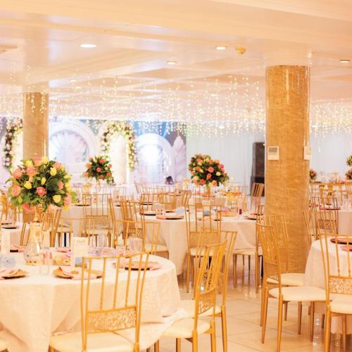 un salón de banquetes con mesas y sillas blancas en MAYFAIR, en Dar es Salaam