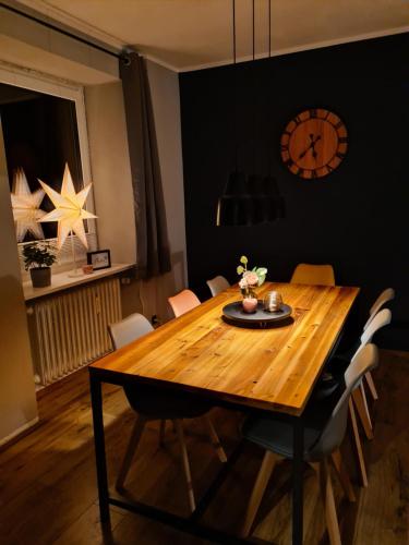 a dining room table with chairs and a clock on the wall at Waldblick Ferienwohnungen in Bonndorf im Schwarzwald
