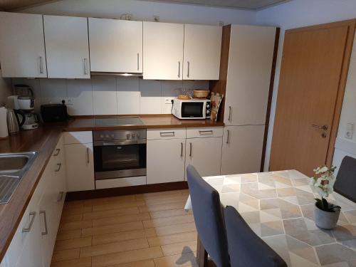 a kitchen with white cabinets and a table and a microwave at Ferienhof Schräder "Ol Deele" in Papenburg