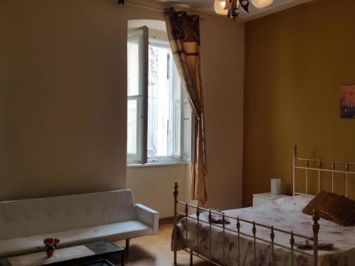 Un dormitorio con una cama y un sofá y una ventana. en Affittacamere Guerrero JR Tra storia e cultura, en Trieste