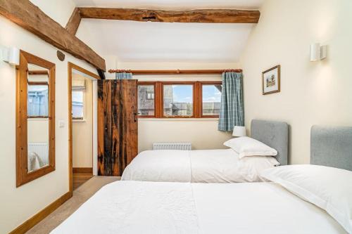 2 camas en una habitación con ventana en Mill Cottage, en Buckinghamshire