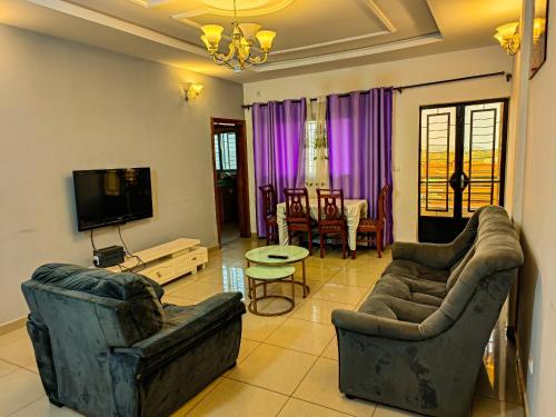 a living room with two couches and a tv at Résidence D in Bafoussam