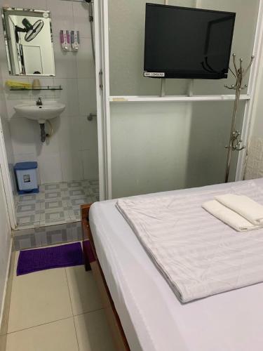 a bathroom with a bed and a sink and a television at Khách sạn Ánh Nguyệt 1 in Ho Chi Minh City